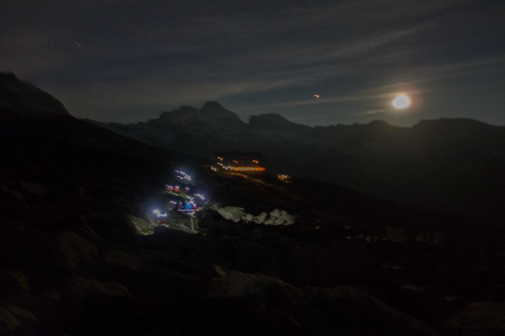 La chenille lumineuse des frontales et en arrière plan le refuge éclairé